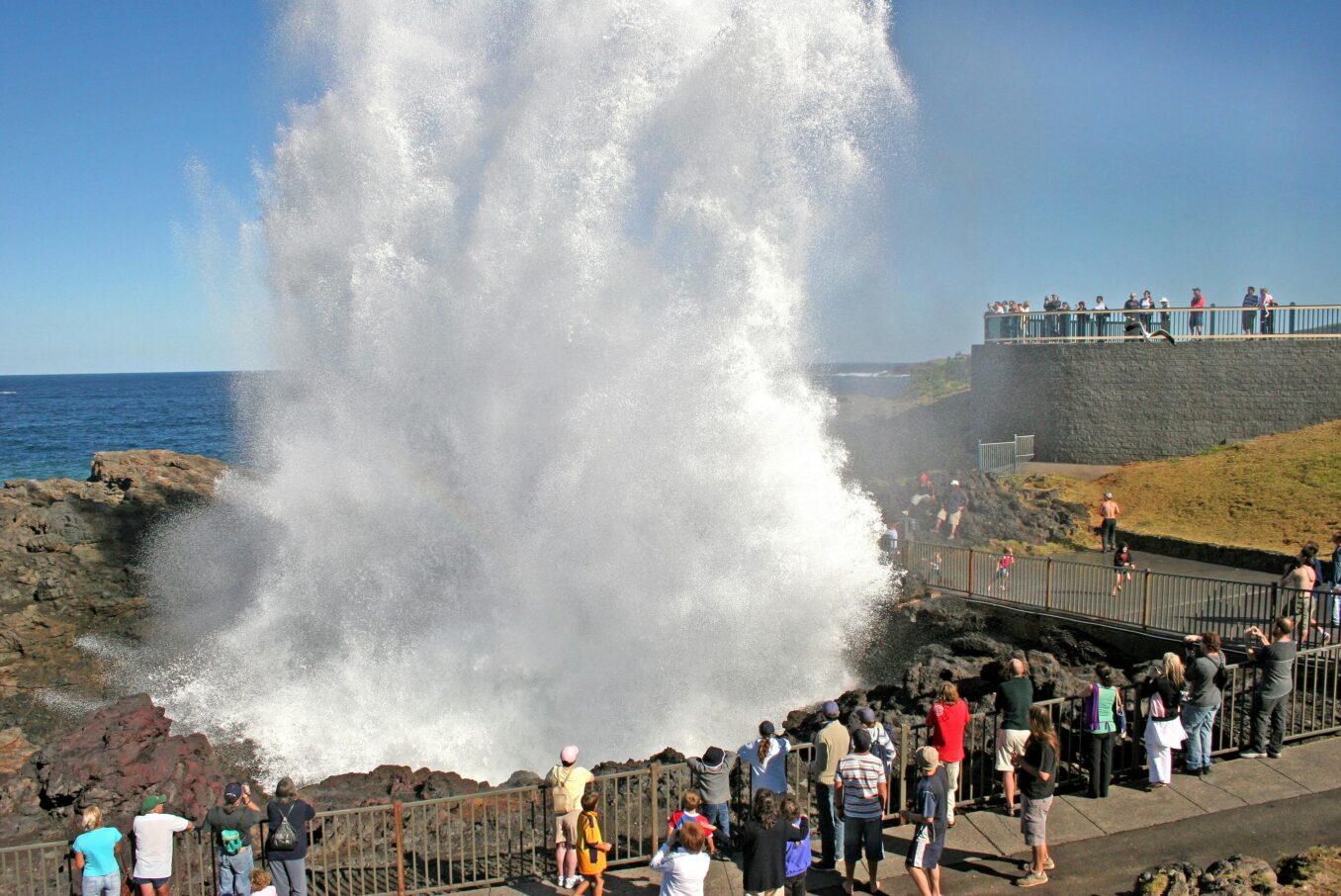A plume of seawater erupting from the Kiama Blowhole beside its viewing platform